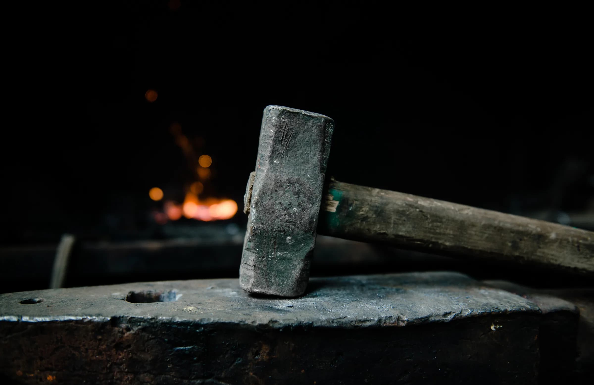 Blacksmith's hammer on the anvil, forge fire behind